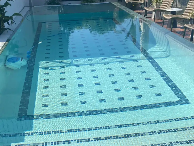 בריכה בצורת L עם מדרגות ישיבה רחבות ומשטח הומוגני